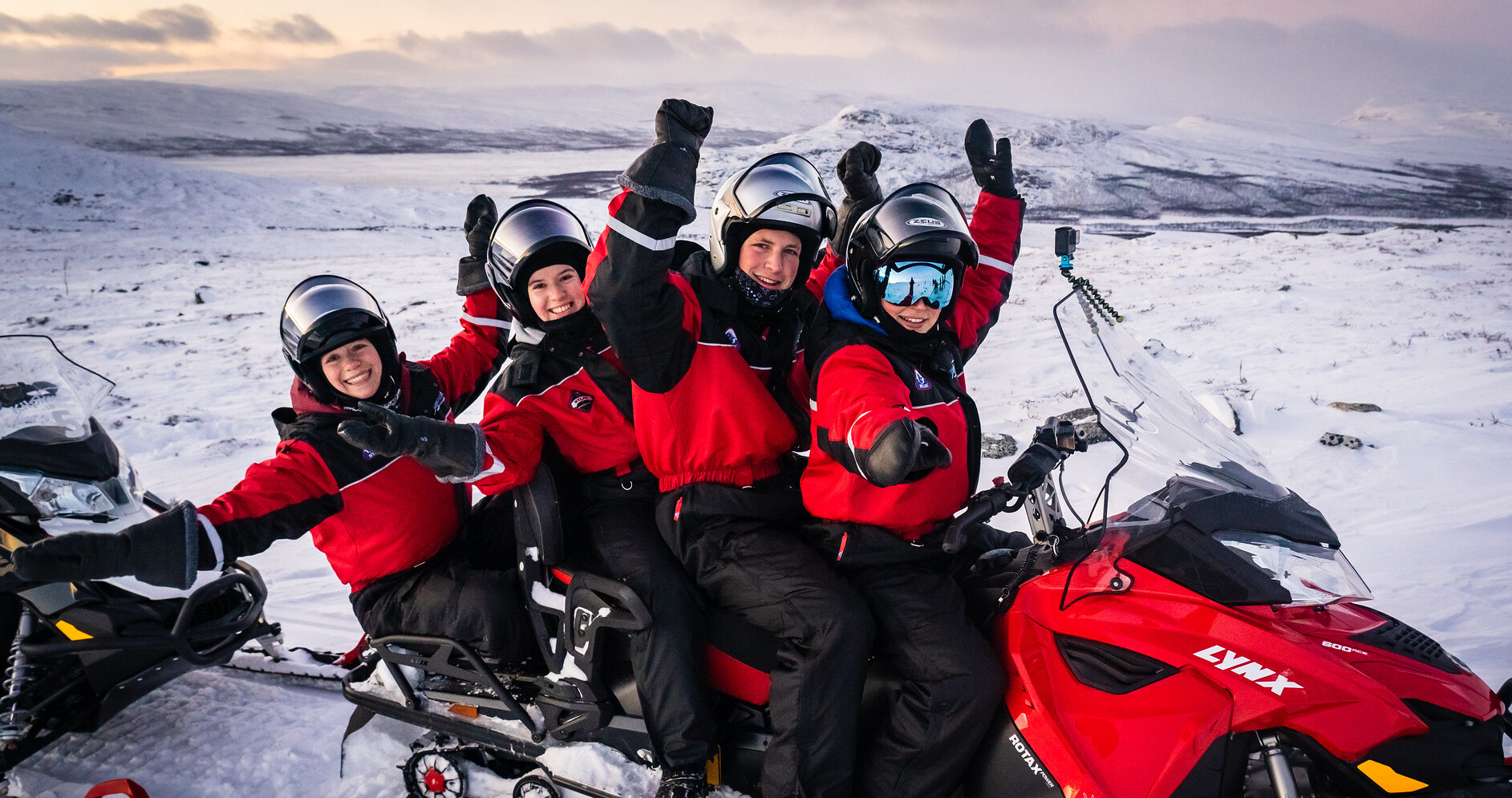 group of people wearing overalls on snowmobile