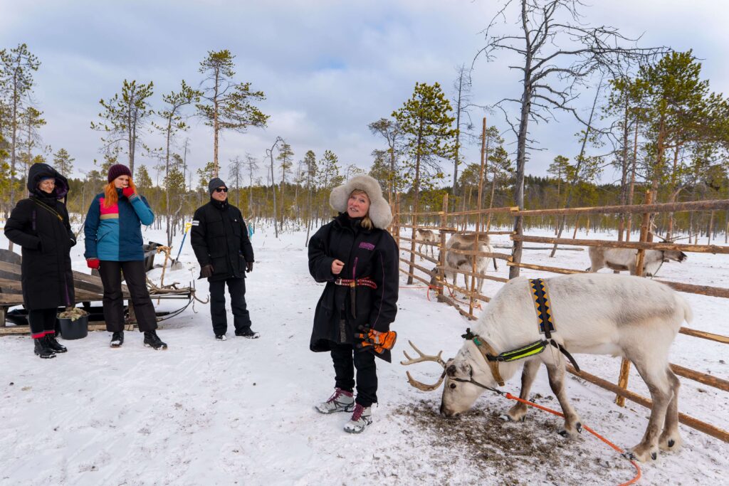 An elder in traditional Sami clothing shares stories with a group of visitors.